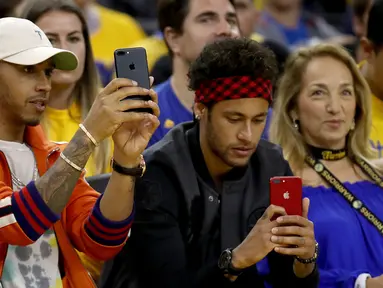 Pembalap Formula 1, Lewis Hamilton dan pemain Barcelona, Neymar Jr merekam pertandingan gim kedua Final NBA antara Cleveland Cavaliers melawan Golden State Warriors di Oracle Arena, Oakland, California, AS, (4/6). (Ezra Shaw/Getty Images/AFP)