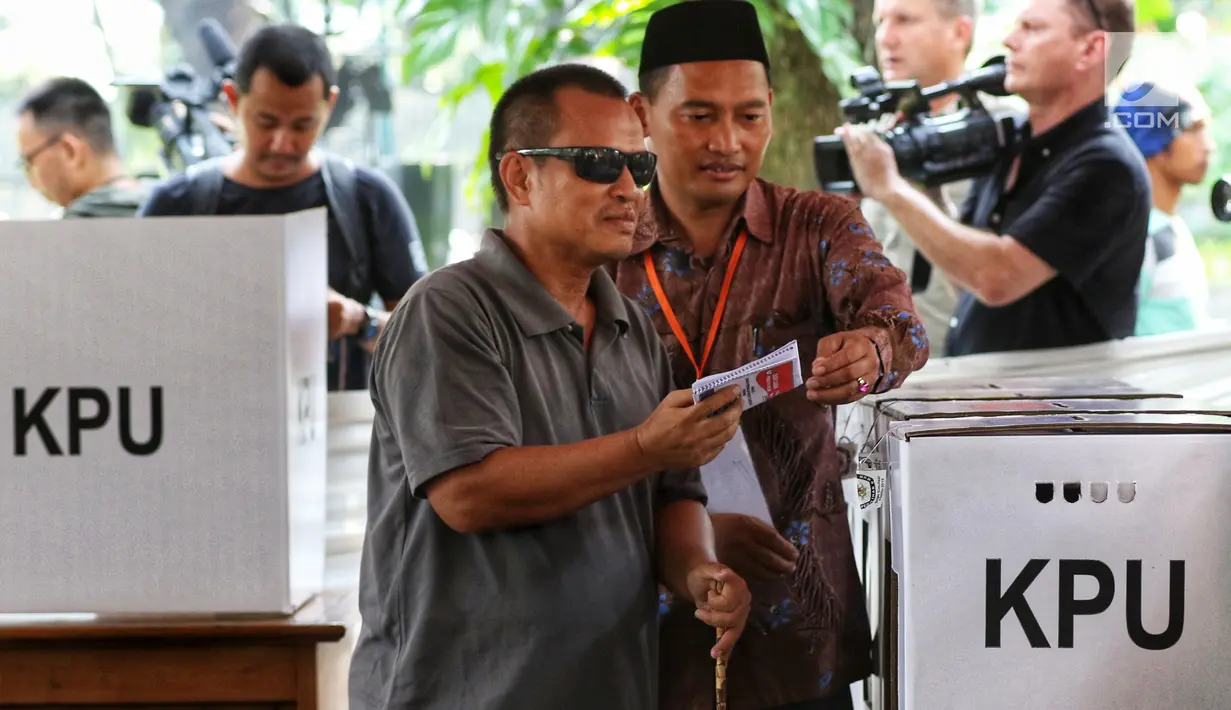 Pemilih disabilitas dibantu pendamping memasukkan surat suara yang telah dicoblos saat mengikuti simulasi Pemilu 2019 di Taman Suropati, Jakarta, Rabu (10/4). Simulasi dilakukan untuk meminimalisir kesalahan dan kekurangan saat pencoblosan pemilu pada 17 April nanti. (Liputan6.com/Johan Tallo)