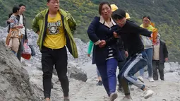 Keluarga dan kerabat korban menuju lokasi sambil membawa alat ritual untuk menenangkan arwah orang yang tewas di lokasi tanah longsor di desa Xinmo, Sichuan, China (25/6). (AP Photo / Ng Han Guan)