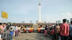 Sejumlah warga antri untuk menaiki kereta wisata di halaman Monumen Nasional, Jakarta, Kamis (7/7). Libur kedua Lebaran dimanfaatkan warga untuk bekunjung ke lokasi wisata bersama keluarga. (Liputan6.com/Yoppy Renato)