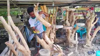 Antoni, pekerja di Rumah Produksi Sahabat Akar dengan gergajinya membuat bentuk rak tanaman hias. (Liputan6.com/M Syukur)