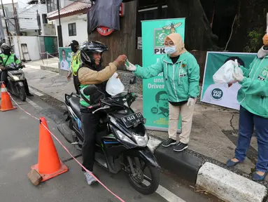 Ojek online (ojol) menerima bantuan berupa bingkisan makan siang dan hand sanitizer di kawasan Jalan Raden Saleh, Jakarta, Selasa (7/3/2020). Bantuan dari DPP PKB guna meringankan beban ojol yang sepi orderan akibat lesunya perekonomian selama pandemi corona Covid-19. (Liputan6.com/Fery Pradolo)