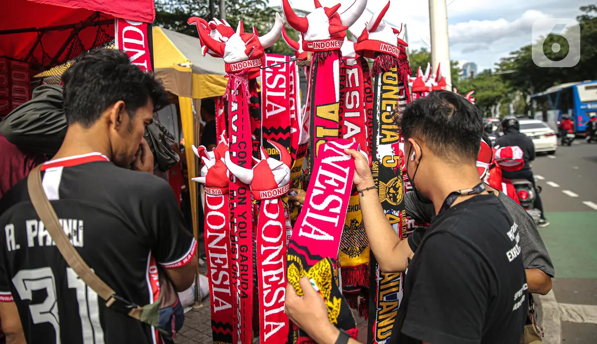 Suporter memilih atribut Timnas Indonesia jelang pertandingan AFF 2022 antara Indonesia melawan Thailand di Stadion Gelora Bung Karno, Jakarta, Kamis (29/12/2022). Atribut timnas Indonesia seperti kaos, syal, dan topi dijual dengan kisaran harga Rp35.000 hingga Rp75.000. (Liputan6.com/Faizal Fanani)
