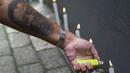 Seorang penggemar dengan tato lengannya bergambar legenda sepak bola Brasil Pele menyalakan lilin saat berjaga di luar pintu masuk Rumah Sakit Albert Einstein di Sao Paulo, Minggu (4/12/2022). Sebelumnya, menurut laporan di Brasil, Pele tengah menjalani perawatan akhir hidupnya setelah tidak menanggapi kemoterapi kanker usus besar yang ia jalani. (Miguel Schincariol / AFP)