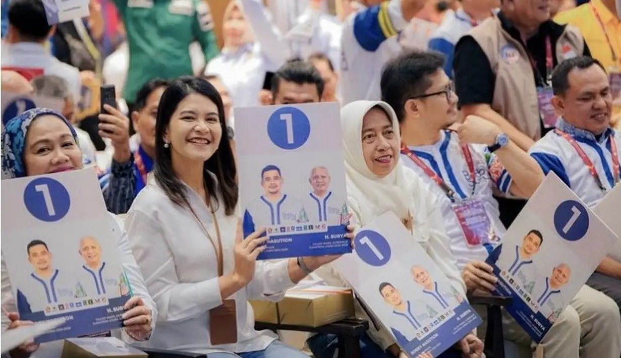 Kahiyang Ayu memilih mengenakan kemeja putih lengan panjang yang cukup fit body. Tampak ia pun mengenakan lanyard coklat. [@bobbynst]