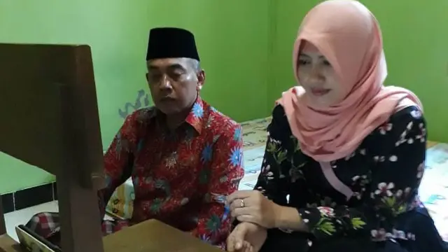 Aiptu Muhamad Anwar Junaidi dan Siti Zulaicha orang tua Zaidan Kamal Anwar pengibar bendera pusaka asal Grobogan, mengikuti upacara bendera di Istana Negara secara virtual di tepi tempat tidur. (Foto: Liputan6.com/Dok Aiptu Muhamad Anwar)