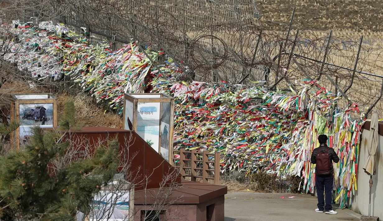 Seorang pria berjalan di dekat pagar kawat yang dihiasi ribuan pita bertuliskan pesan damai antara Korea Selatan dan Korea Utara di Paviliun Imjingak, Paju, Korea Selatan, Senin (5/3). (AP Photo/Lee Jin-man)