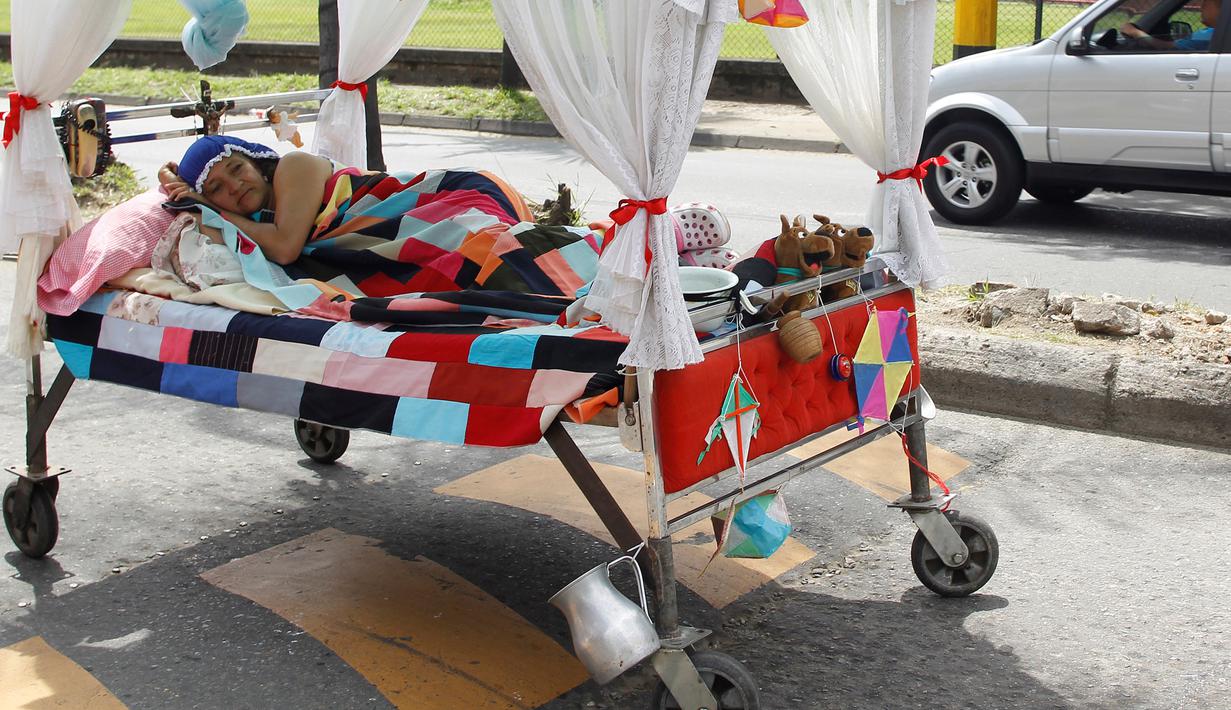 Seorang wanita saat tiduran di atas kasur yang dibawa ke jalan saat menikmati acara Hari Malas Sedunia di Ibague, Kolombia, (14/8). Dalam acara unik ini, peserta turun ke jalan beserta tempat tidurnya. (REUTERS/Fredy Builes)