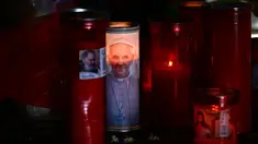 Lilin diletakkan di patung Yohanes Paulus II di luar Rumah Sakit Universitas Gemelli di mana Paus Fransiskus dirawat di rumah sakit karena pneumonia, di Roma pada tanggal 3 Maret 2025. (Filippo MONTEFORTE/AFP)