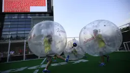 Para pemain mengolah si kulit bundar dari dalam sebuah gelembung berbentuk bola di Beijing, Kamis (10/7/14). (REUTERS/Kim Kyung-Hoon)