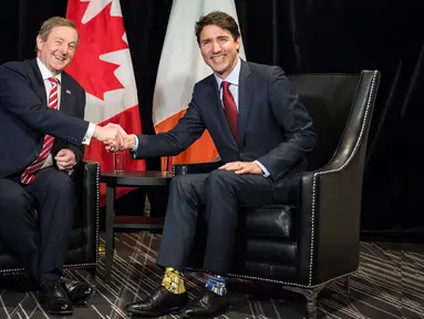 PM Kanada Justin Trudeau berjabat tangan dengan PM Irlandia, Enda Kenny sebelum menggelar pertemuan di Montreal, Kamis (4/5). Trudeau tampak mengenakan kaus kaki Star Wars dengan motif dan warna tak serasi. (Paul Chiasson/The Canadian Press via AP)