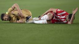 Reaksi kesakitan pemain Barcelona, Jordi Alba (kiri) dan pemain Almeria, Leo Baptistao pada laga lanjutan Liga Spanyol 2022/2023 yang berlangsung di Power House Stadium, Senin (27/02/2023) dini hari WIB. (AFP/Jorge Guerrero)