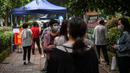 Warga mengenakan masker menunggu dalam barisan untuk tes virus corona di lingkungan di Wuhan, provinsi Hubei, China, Jumat (15/5/2020). Pihak berwenang Kota Wuhan menggelar tes massal terhadap 11 juta warganya untuk mencegah gelombang kedua pandemi Covid-19. (Hector RETAMAL/AFP)