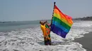 Seorang dukun Peru memegang bendera pelangi selama ritual untuk menyambut tahun baru  di pantai Agua Dulce, Lima, Kamis (27/12). Ritual dimaksudkan untuk membawa kekuatan dan energi ke seluruh dunia sehingga ada kedamaian dan ketenangan. (AP/Martin Mejia)