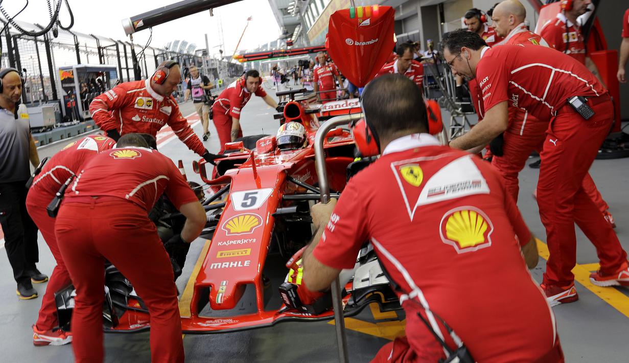 Tim mekanik Ferrari sibuk memperbaiki mobil Sebastian Vettel pada sesi latihan bebas F1 GP Singapura di Marina Bay City Circuit, (15/9/2017). (AP/Wong Maye-E)