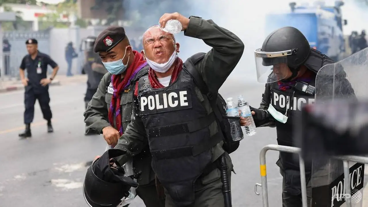 Seorang polisi bereaksi setelah gas air mata dilemparkan selama unjuk rasa anti-pemerintah di Bangkok pada 17 November 2020.