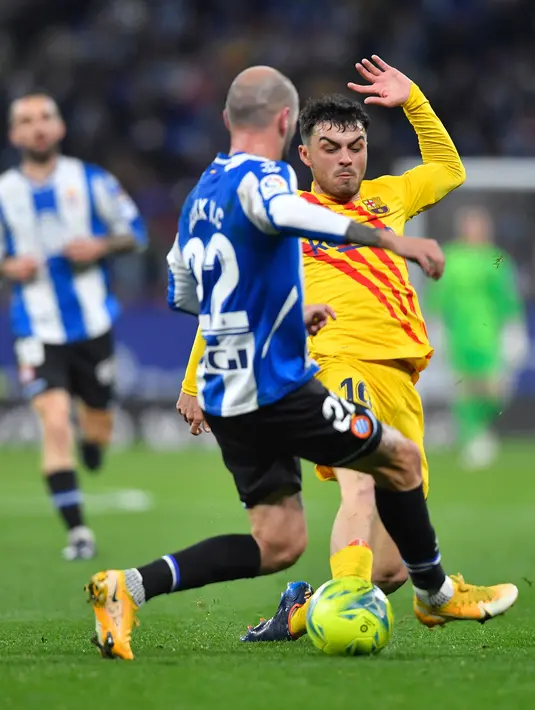 Bek Espanyol Aleix Vidal (kiri) berebut bola dengan gelandang Barcelona Pedri pada jornada ke-24 Liga Spanyol 2021/22 di RCDE Stadium, Senin dini hari WIB (14/2/2022). Espanyol dan Barcelona bermain imbang 2-2. (Pau BARRENA / AFP)