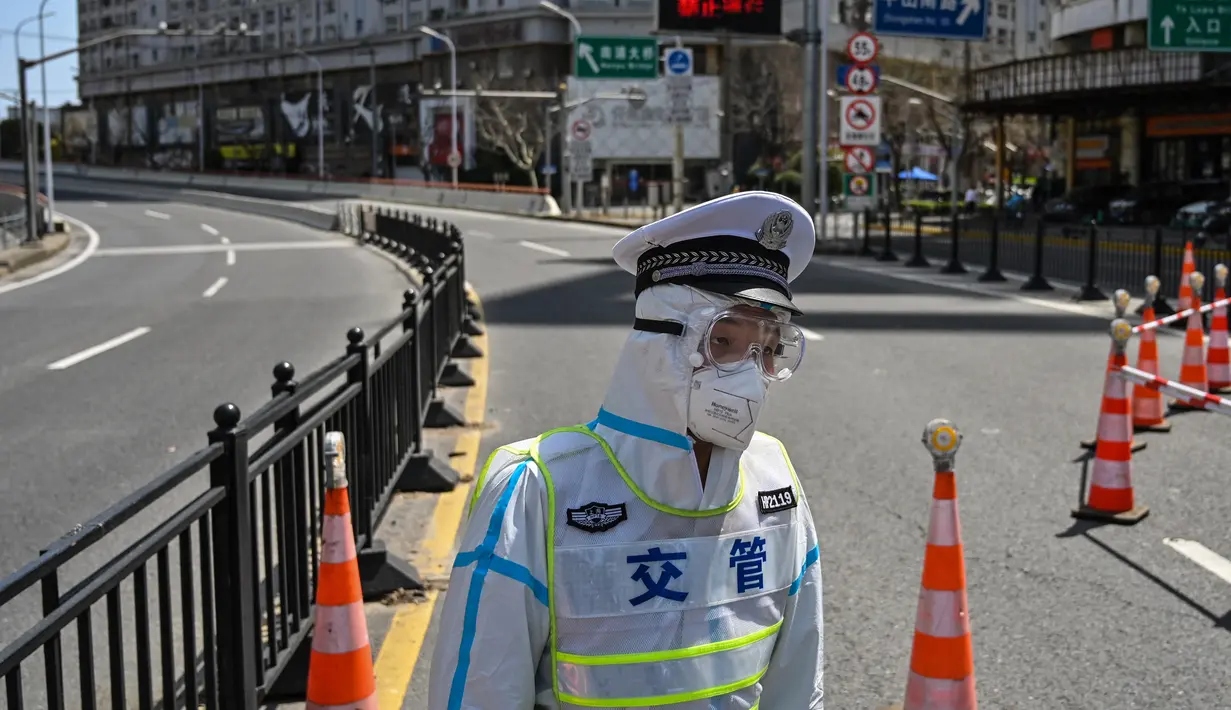 Seorang petugas transit mengenakan pakaian pelindung mengontrol akses ke jembatan ke arah distrik Pudong dalam penguncian sebagai tindakan pencegahan virus corona Covid-19  di Shanghai (29/3/2022). (AFP/Hector Retamal)