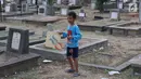 Seorang anak bermain layangan di TPU Menteng Pulo, Jakarta, Kamis (18/10). Padatnya pemukiman penduduk serta gedung bertingkat di kawasan tersebut menyebabkan anak-anak terpaksa bermain di tempat yang tidak semestinya. (Liputan6.com/Immanuel Antonius)