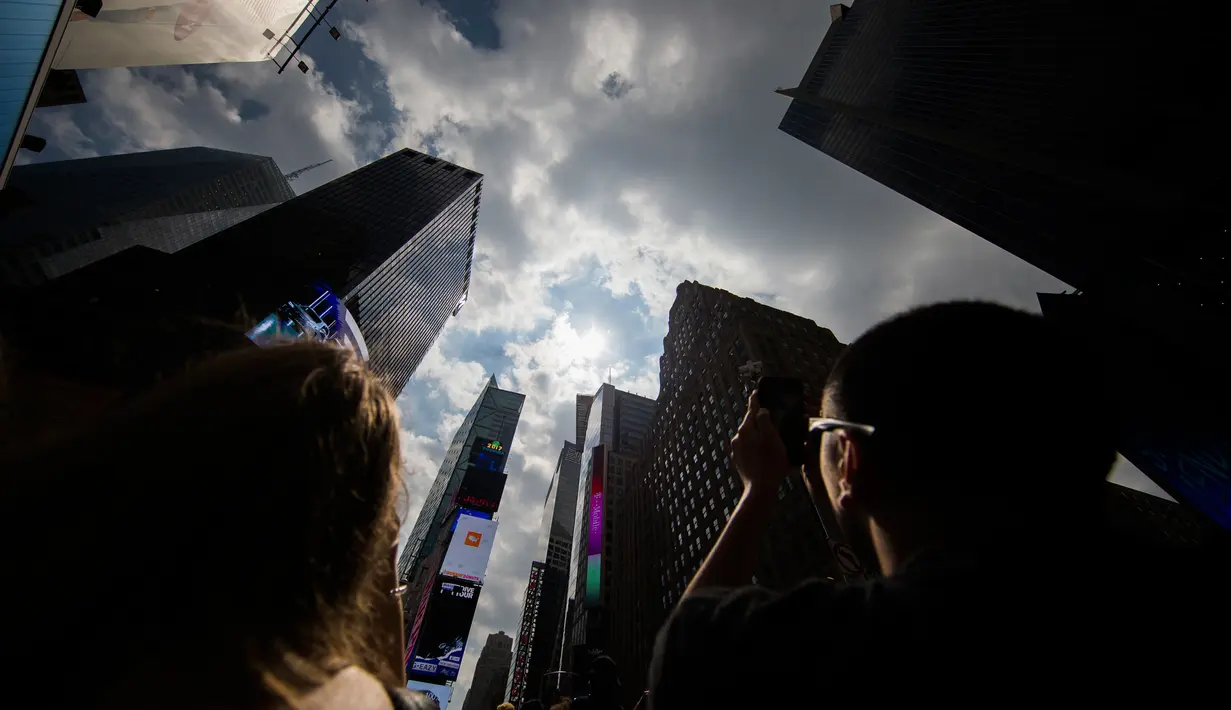 Sejumlah orang mengabadikan fenomena gerhana matahari parsial di langit New York, Senin (21/8). Gerhana matahari akan terjadi selama 100 menit dan selama dua menit kondisi langit akan gelap gulita di siang hari. (AP Photo/Michael Noble Jr.)