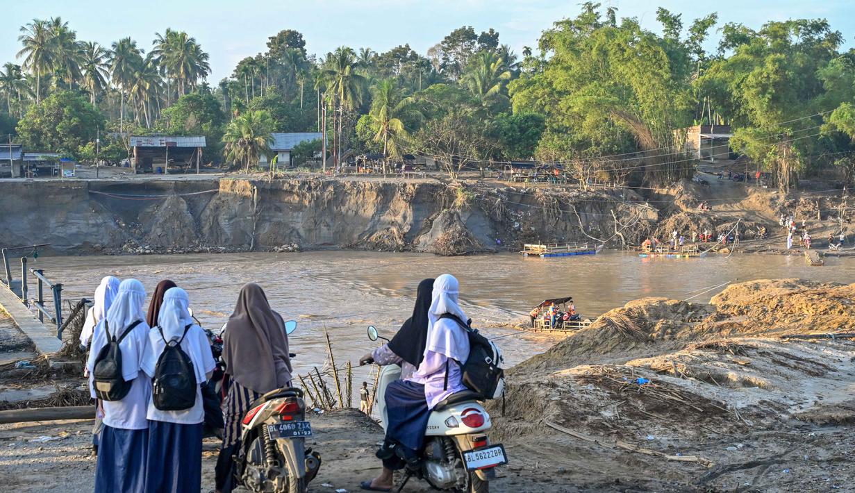 Namun, pelaksanaan Pembelajaran Tatap Muka (PTM) pada minggu pertama dan kedua Januari 2026 akan difokuskan pada kegiatan trauma healing. Tampak dalam foto, para siswa menunggu untuk menggunakan perahu darurat untuk menyeberangi Sungai Peusangan pasca banjir bandang yang menghancurkan desa-desa di sekitarnya di kabupaten Bireuen, provinsi Aceh, Indonesia pada Senin 5 Januari 2026. (CHAIDEER MAHYUDDIN/AFP)