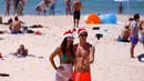 Dua turis mengenakan topi natal berselfie saat merayakan hari Natal di Bondi Beach Sydney pada Hari Natal di Australia, (25/12). (REUTERS/David Gray)