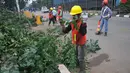 Petugas memotong batang pohon yang telah ditebang di sepanjang jalan DI. Panjaitan, Kebon Nanas, Jakarta, Senin (21/3). Penebangan pohon-pohon itu untuk pelebaran jalan terkait pembangunan Jalan Tol Becakayu. (Liputan6.com/Gempur M Surya)