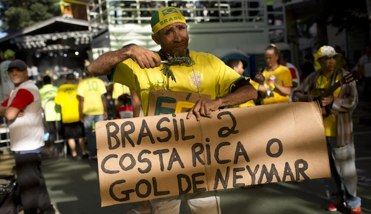 Seorang suporter menunjukan hasil akhir Brasil melawan Kosta Rika pada laga grup E Piala Dunia 2018 di Rio de Janeiro, Brasil, (22/6/2018). Brasil menang 2-0. (AP/Silvia Izquierdo)