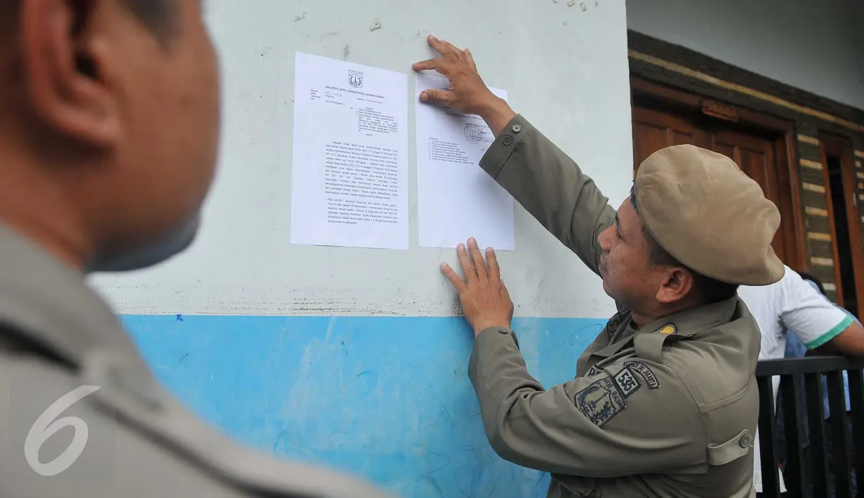 Satpol PP menempelkan surat peringatan kedua (SP2) di salah satu rumah warga di Kalijodo, Jakarta, Kamis (25/2). Dalam SP2 tersebut, warga Kalijodo diberi waktu 3×24 jam untuk mengosongkan/membongkar sendiri bangunan mereka. (Lputan6.com/Gempur M Surya)