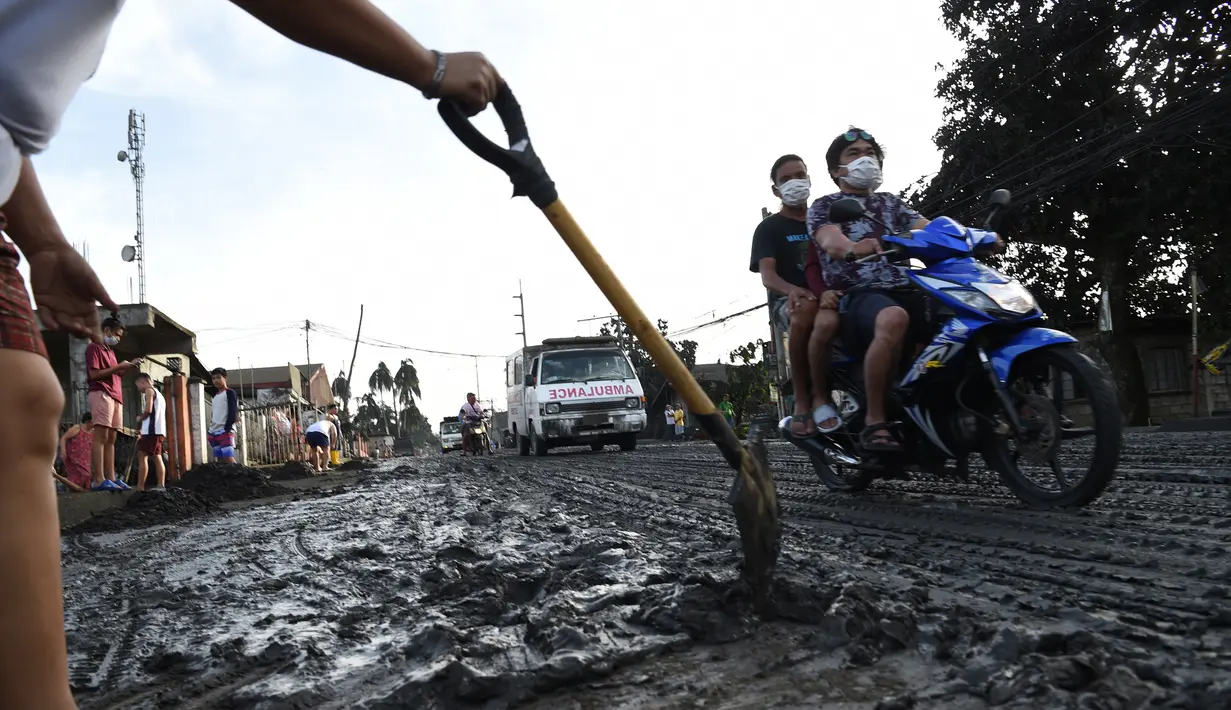 Warga membersihkan jalanan dari abu vulkanik setelah erupsi Gunung Taal di Tagaytay, Provinsi Cavite, Filipina, Senin (13/1/2020). Gunung yang terakhir meletus pada tahun 1977 tersebut melontarkan abu vulkanik mencapai 50.000 kaki (15.000 meter) ke atmosfer. (TED ALJIBE/AFP)