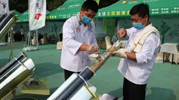 Dua koki memasukkan daging sate ke dalam tabung logam dan dimasak menggunakan kompor tenaga surya di Dezhou, Shandong Timur, Cina, 2 Agustus 2018. Koki memasak pada festival masak menggunakan kompor tenaga surya di Cina. (AP Foto/Fu Ting)