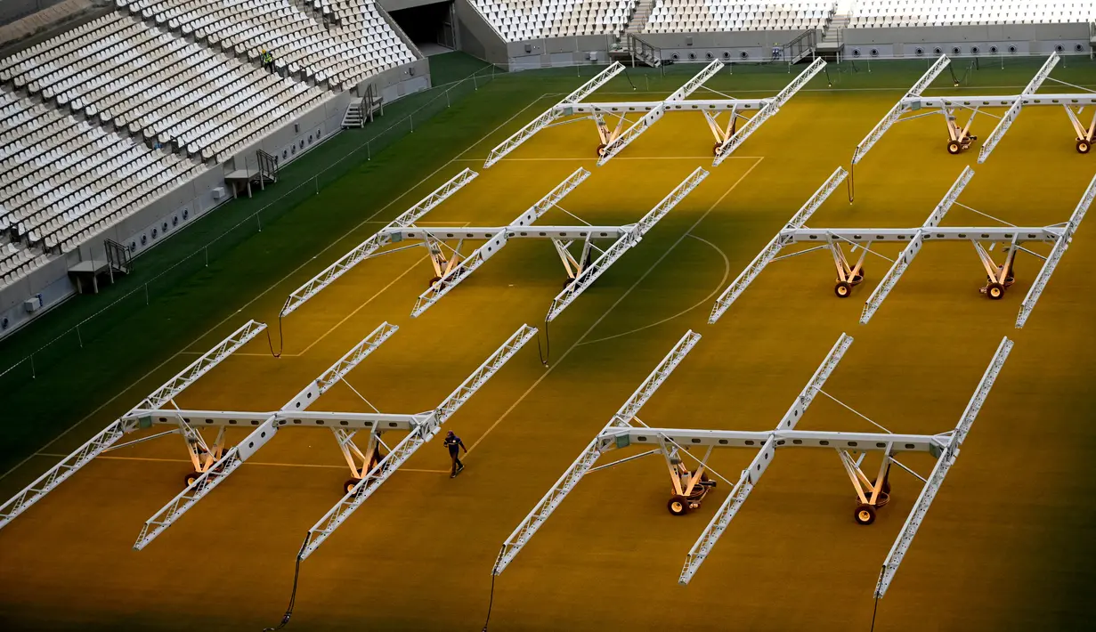 Seorang pria bekerja di lapangan Lusail Stadium, Lusail, Qatar, 28 Maret 2022. Stadion berkapasitas 80 ribu penonton yang terletak di pinggiran Ibu Kota Doha ini akan menjadi tuan rumah final Piala Dunia 2022 pada bulan Desember mendatang. (GABRIEL BOUYS/AFP)