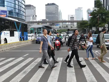 Warga menyebrang jalan Sudirman di kawasan Tosari, Jakarta, Jumat (14/12). Penggunaan pelican crossing di kawasan ini menggantikan fungsi Jembatan Penyebrangan Orang (JPO) Tosari yang akan dibongkar. (Liputan6.com/Helmi Fithriansyah)