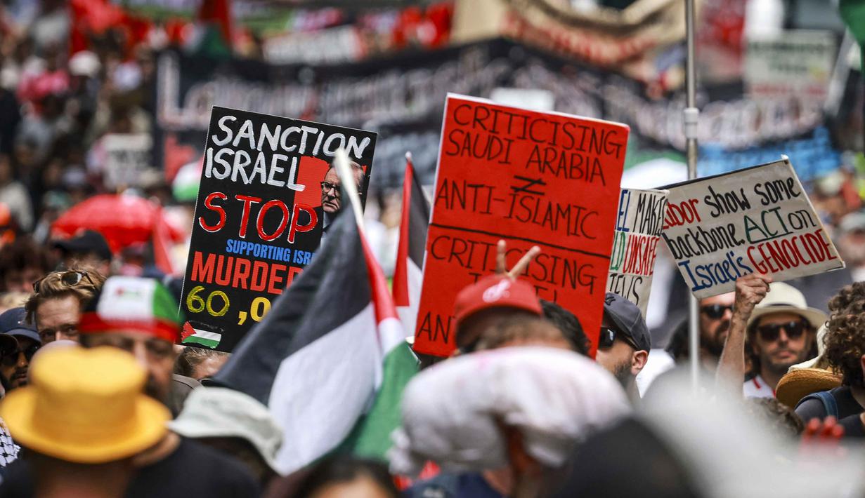 Angka ini jauh lebih tinggi dibanding laporan resmi otoritas kesehatan Gaza yang mencatat sekitar 49.000 kematian. Tampak dalam foto, para demonstran pro-Palestina membawa bendera, spanduk, dan plakat saat mereka berbaris berunjuk rasa di jalanan kota Sydney, Australia, Minggu 22 Februari 2026. (DAVID GRAY/AFP)