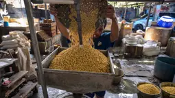 Fluktuasi harga kedelai yang terlalu cepat menyulitkan perajin dalam mengatur produksi dan berpotensi memicu keluhan konsumen. Tampak dalam foto, seorang pekerja membilas kedelai di pabrik tahu, Surabaya, Jawa Timur pada Kamis 5 Februari 2026. (JUNI KRISWANTO/AFP)