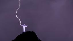 Petir menyambar tangan Christ the Redeemer atau Patung Kristus Penebus di gunung Corcovado di Rio de Janeiro, Brasil, Selasa (21/2/2023). Tingginya patung juga membuatnya beberapa kali tersambar petir saat badai menerjang kota tersebut. (Photo by MAURO PIMENTEL / AFP)