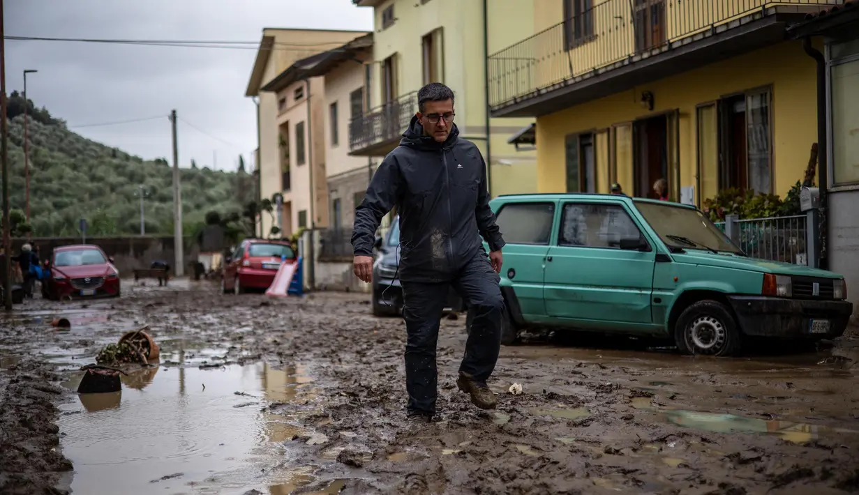 Seorang pria berjalan di lumpur di Montemurlo setelah hujan deras, pada 3 November 2023. (Federico SCOPPA/AFP)