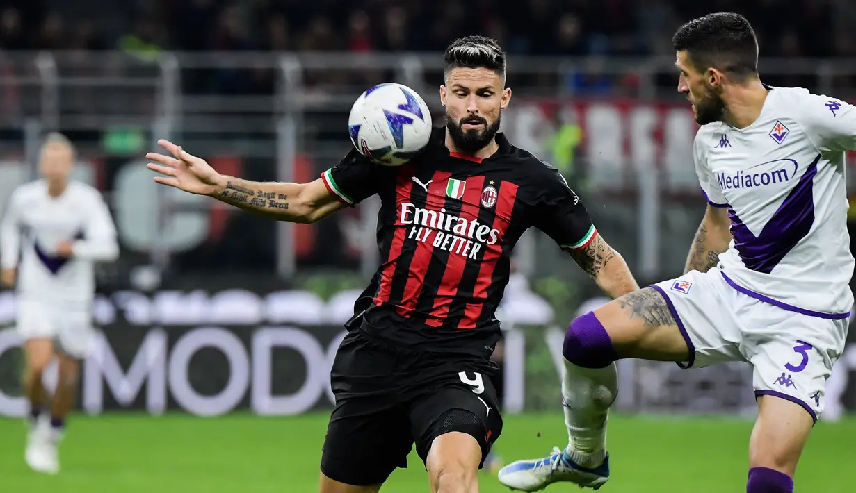 Penyerang AC Milan Olivier Giroud berebut bola dengan bek Italia Fiorentina Cristiano Biraghi pada duel pekan ke-15 Serie A 2022/2023 di San Siro, Senin (14/11/2022). AC Milan terpaut delapan angka di belakang Napoli yang menjadi pemuncak. (Filippo MONTEFORTE / AFP)