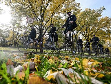 Para penggemar sepeda yang mengenakan pakaian bersejarah mengendarai sepeda yang mereka sebut penny-farthing, atau yang juga dikenal sebagai high wheel, dalam kompetisi tradisional 'One Mile Race' di Taman Letna, Praha, Republik Ceko, pada 1 November 2025. Mengenakan kostum bersejarah, penggemar sepeda model kuno yang disebut 'penny-farthings' berkumpul di Taman Letna, Praha, Republik Ceko, pada 1 November 2025. (Michal Cizek/AFP)