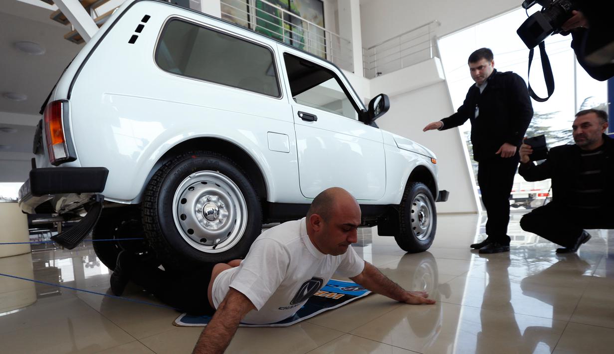 Ekspresi Norik Yajian menahan sakit ketika tubuhnya dilindas sebuah mobil di Tbilisi, Georgia, Selasa (16/2). Atraksi ini nekat dilakukan Norik untuk memecahkan rekor Guinness. (REUTERS/David Mdzinarishvili)