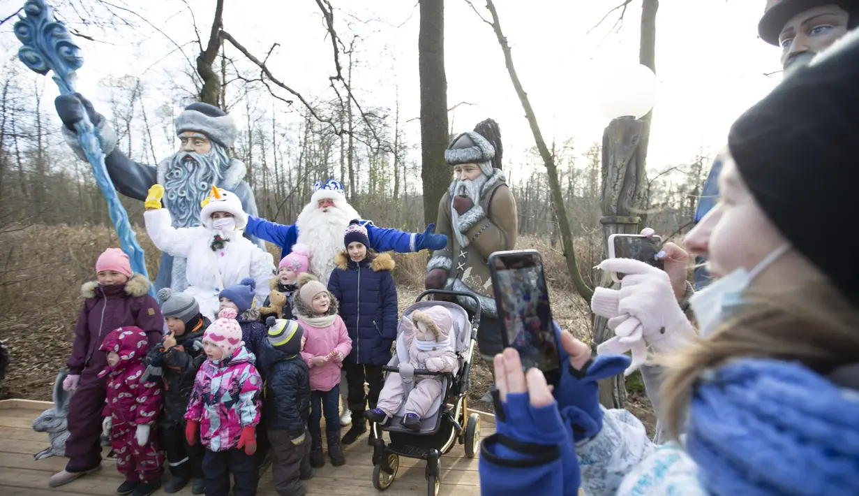 Dua staf yang mengenakan kostum karakter dongeng Rusia, Kakek Frost dan Putri Salju, berpose bersama anak-anak untuk difoto dalam pembukaan "Jalur Dongeng" di "Kediaman Kakek Frost" di Moskow, Rusia (18/11/2020). (Xinhua/Alexander Zemlianichenko Jr)