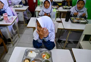 Para siswa berdoa sebelum menyantap makanan yang dipasok oleh program Makan Bergizi Gratis (MBG) di sebuah sekolah dasar, Banda Aceh pada Kamis 30 Oktober 2025. Sejak awal tahun 2025, program Makan Bergizi Gratis (MBG) di Banda Aceh diketahui telah berjalan baik. (CHAIDEER MAHYUDDIN/AFP)