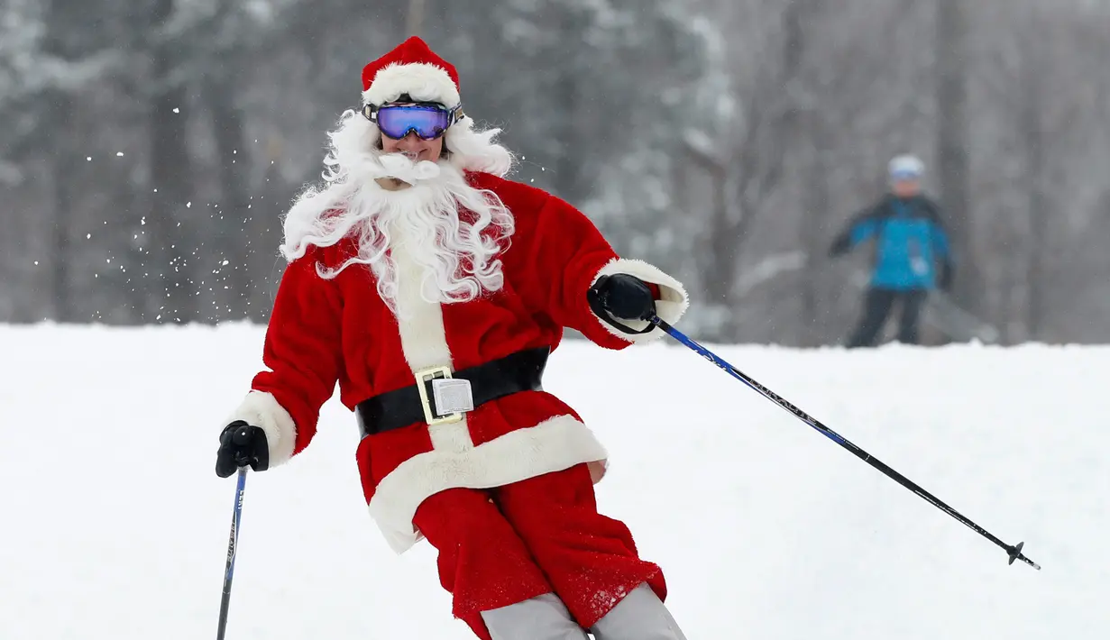 Pemain ski berpakaian Santa Claus menuruni lereng gunung saat Santa Sunday ke-19 di Newry, Maine, AS, Minggu (2/12). Keuntungan acara Santa Sunday digunakan untuk amal. (AP Photo/Robert F. Bukaty)