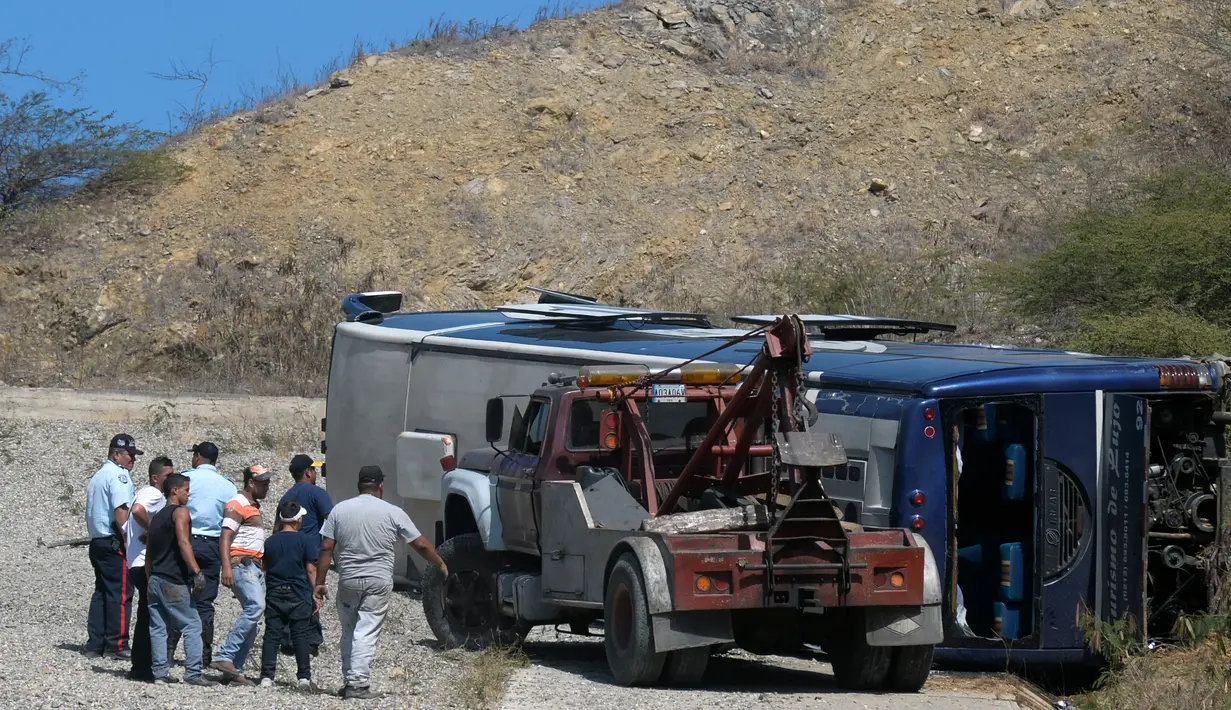 Mobil derek berusaha membalikkan sebuah bus yang terbalik di jalan raya Caracas-La Guaira, Venezuela, Rabu (10/2). Bus berisi pemain tim sepak bola Argentina Huracan itu terbalik saat menuju Bandara Internasional Simon Bolivar. (AFP/FEDERICO PARRA)