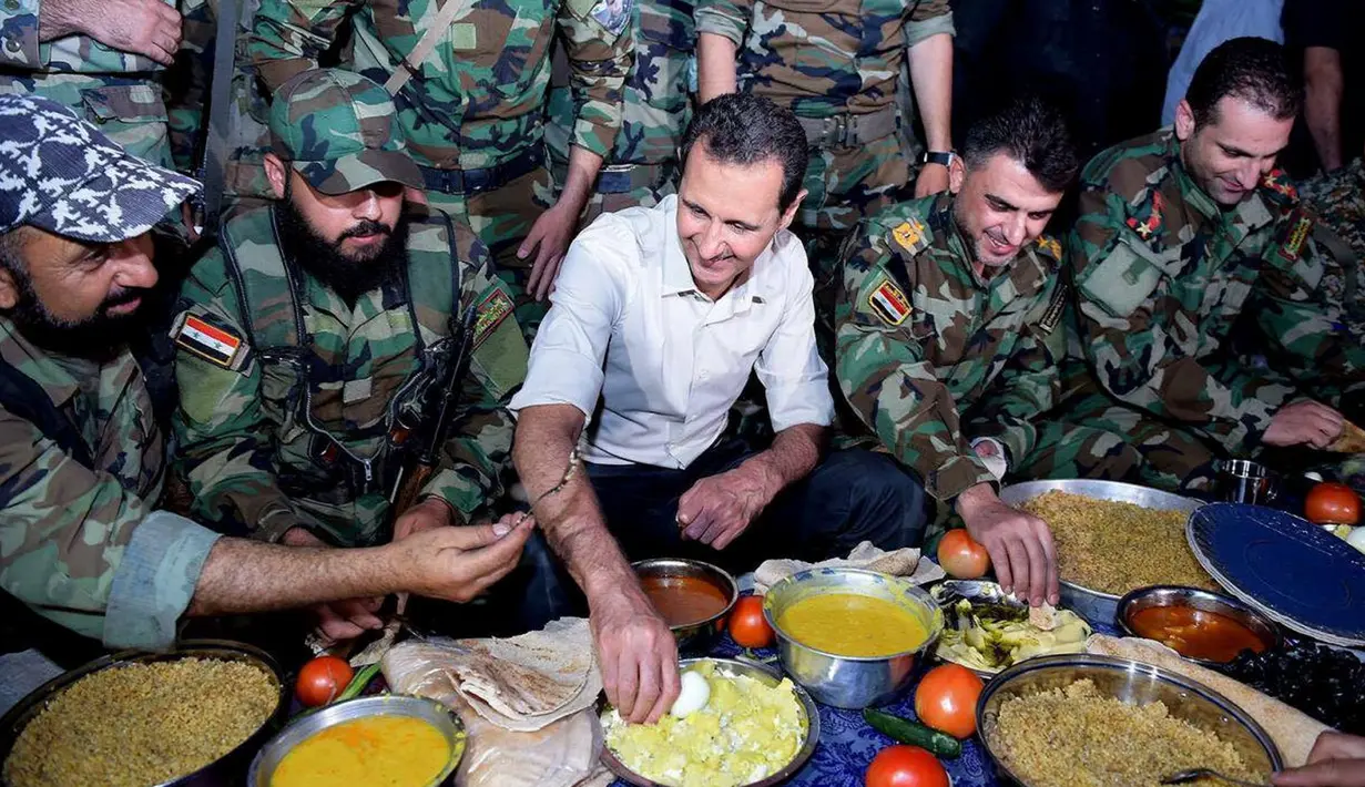 Presiden Suriah Bashar al-Assad dan pasukan setianya melahap hidangan buka puasa di Desa Marj al-Sultan, timur Ghouta, Damaskus, Suriah, Minggu (26/6). (REUTERS/Sana)