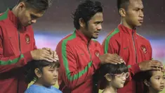 Gelandang Timnas Indonesia, Ilham Udin Armaiyn, melindungi seorang anak dari hujan saat akan melawan Islandia pada laga persahabatan di SUGBK, Jakarta, Minggu (14/1/2018). Timnas Indonesia kalah 1-4 dari Islandia. (Bola.com/Vitalis Yogi Trisna)