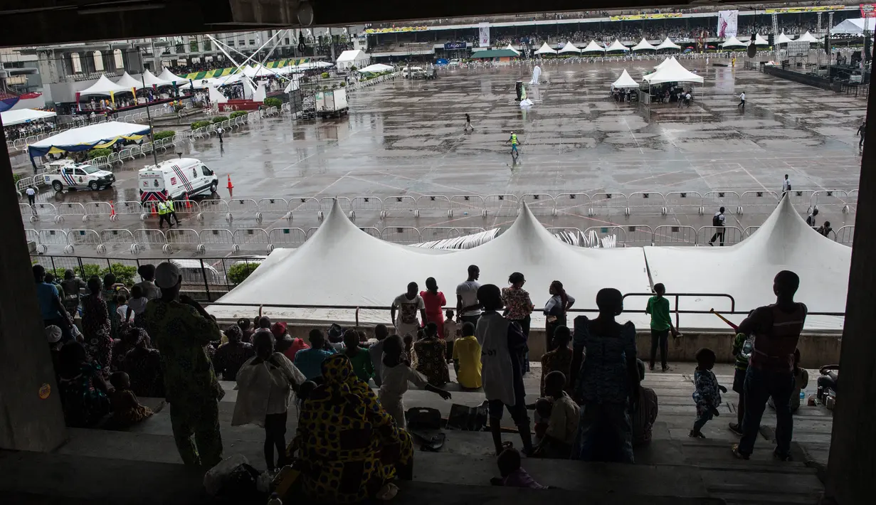 Sejumlah orang duduk untuk menonton Festival Eyo di Tafawa Balewa Square di Lagos, Nigeria (20/5). (AFP Photo/Stefan Heunis)