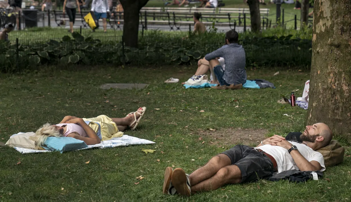 <p>Sejumlah warga beristirahat di tempat teduh saat siang hari yang panas di Washington Square Park di New York City (17/7/2019). Gelombang panas besar akan mempengaruhi hampir dua pertiga dari Amerika Serikat, dengan Pantai Timur dan Midwest. (AFP Photo/Drew Angerer)</p>
