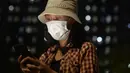 Seorang wanita yang mengenakan masker mengoperasikan gawai di uar RS Darurat Wisma Atlet, Jakarta, Selasa (22/6/2021). Bertepatan dengan HUT ke-494 DKI Jakarta, ada peningkatan kasus COVID-19 yang sudah memasuki fase kritis. (merdeka.com/Imam Buhori)