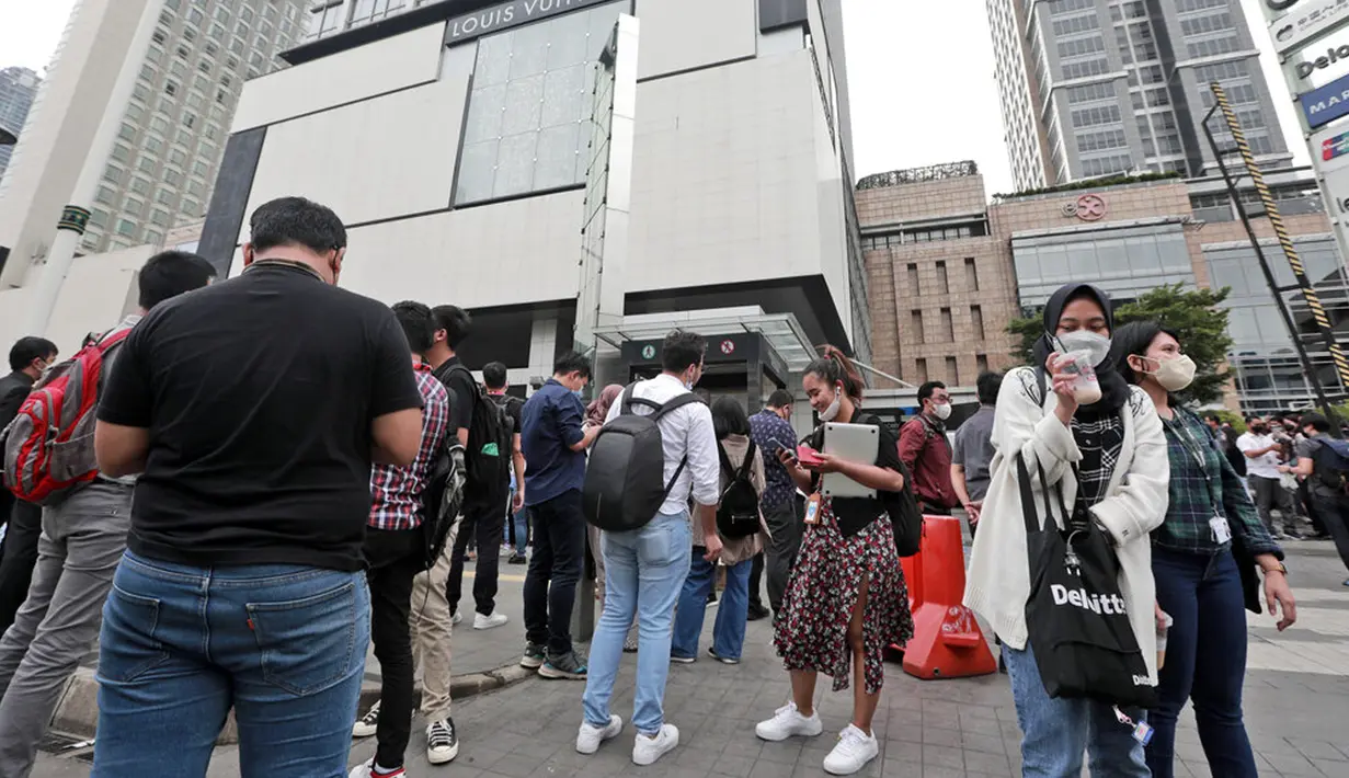 Warga menunggu di luar gedung perkantoran setelah gempa mengguncang Jakarta, Jumat (14/1/2022). Gempa magnitudo 6,7 yang berpusat di Banten pada pukul 16.05 WIB membuat kepanikan di berbagai daerah. (AP Photo)